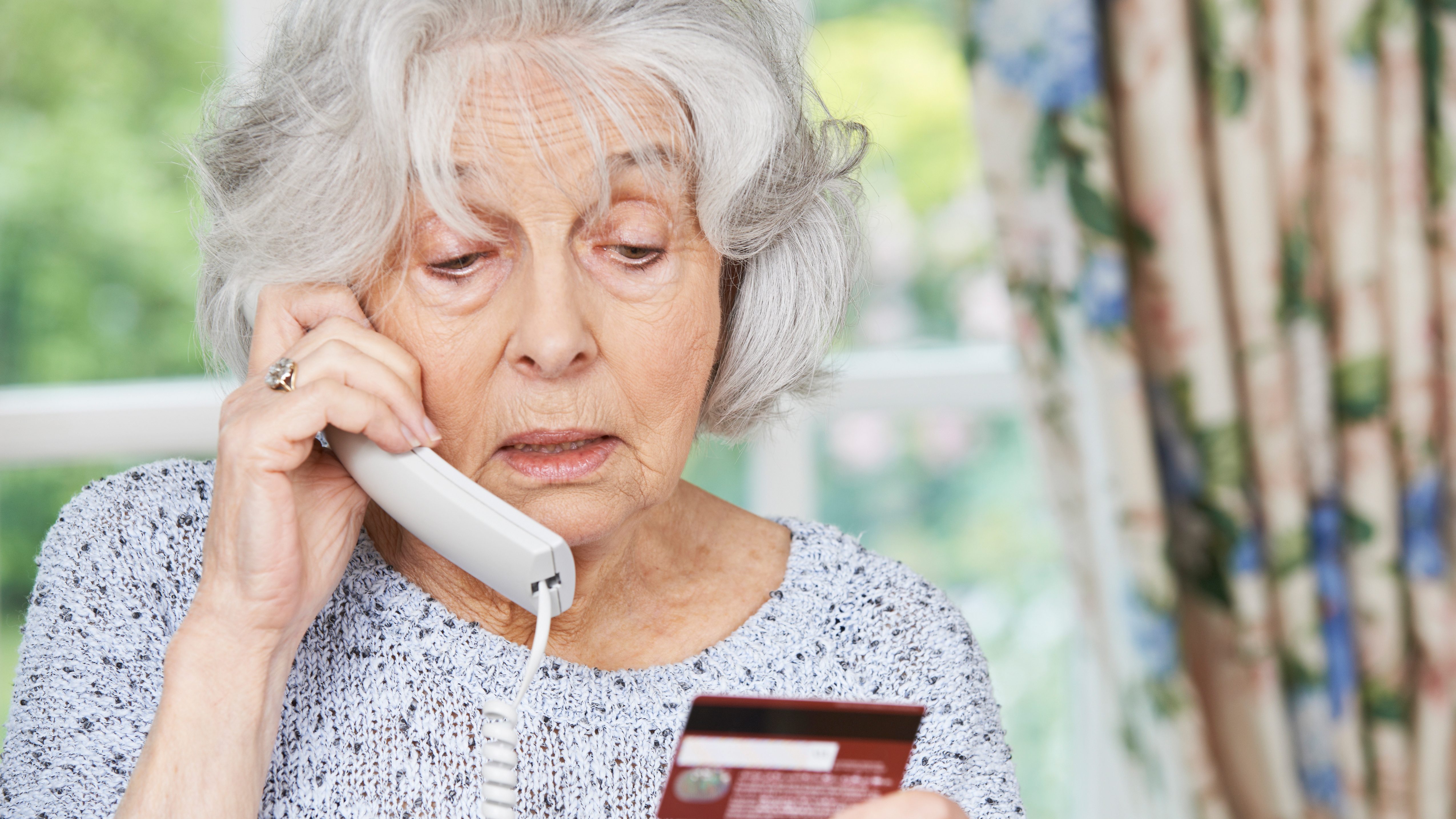 Senior woman reads credit card into into phone