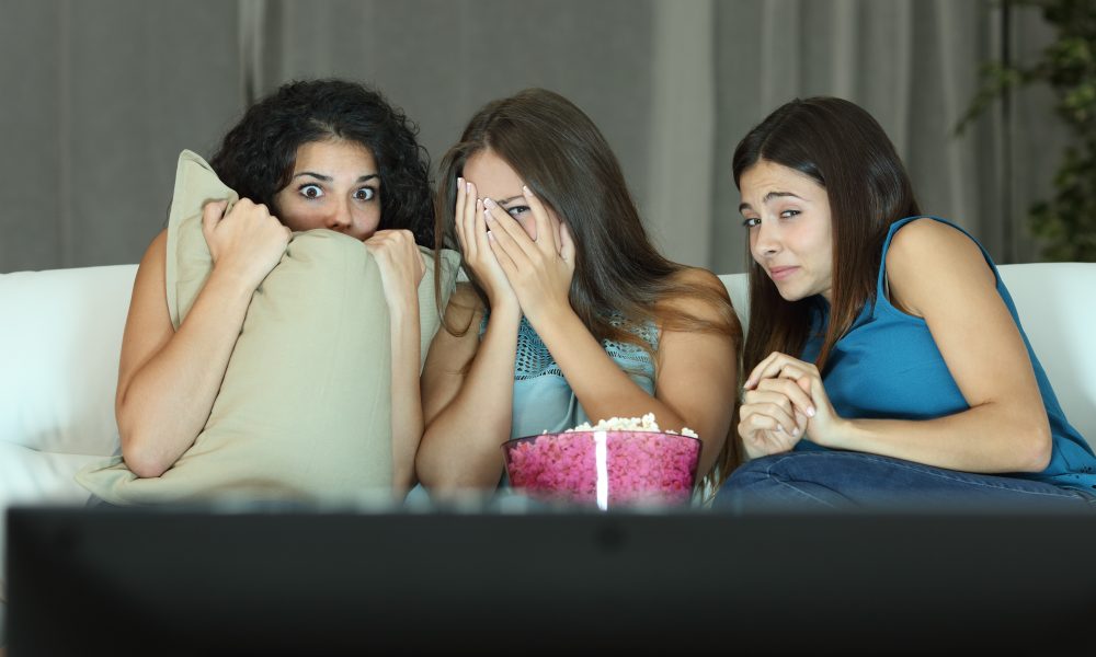 Women watch scary movie at home
