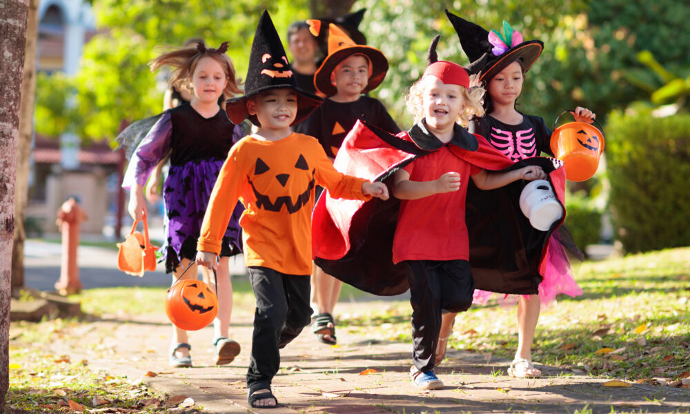 Kids in Halloween costumes run while trick-or-treating
