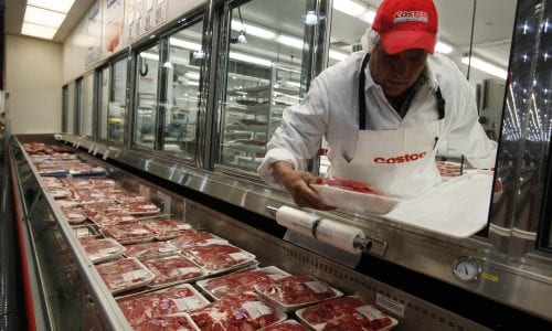 Butcher places meat in case at Costco