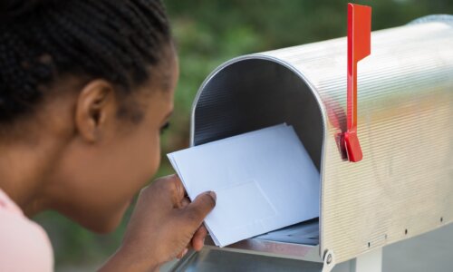 young woman putting letter in mailbox