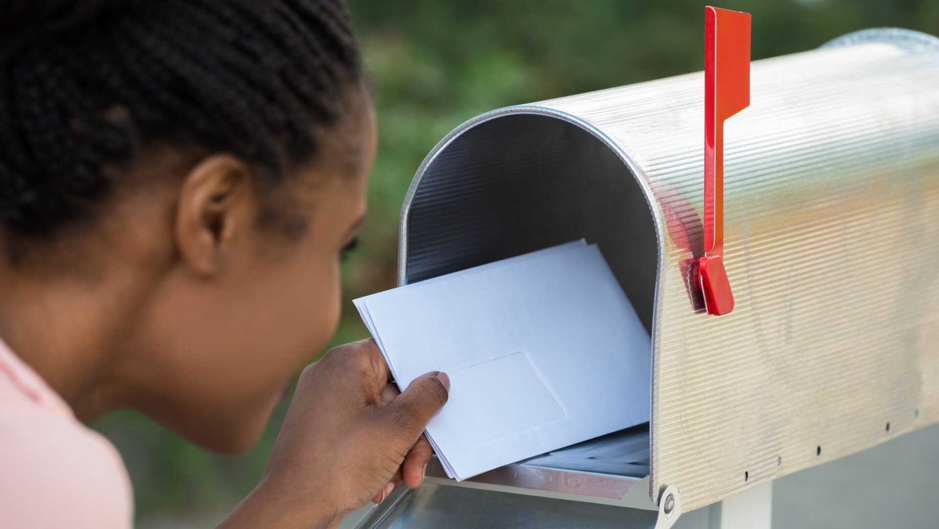 young woman putting letter in mailbox