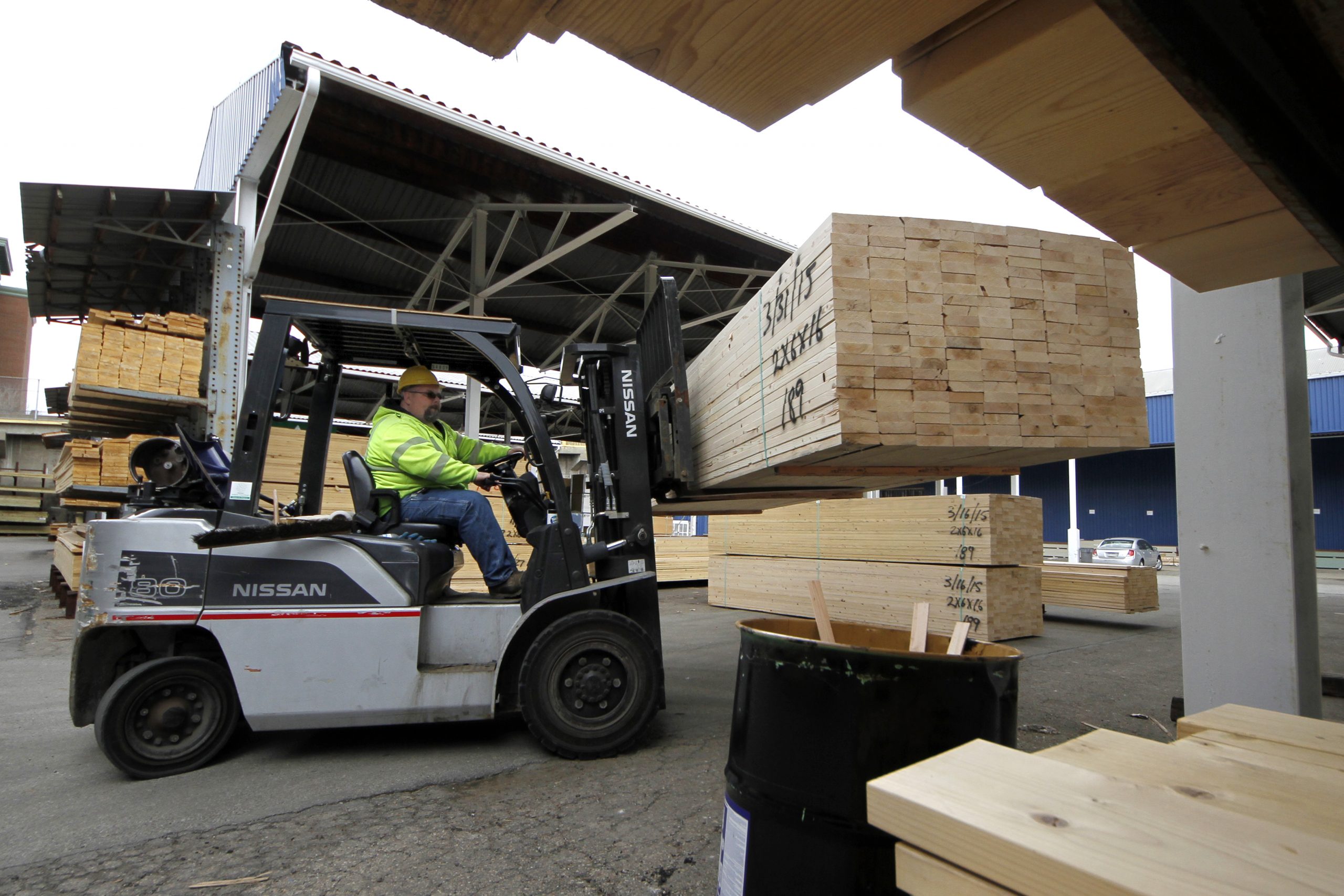 Man in forklift moves 2x4s at lumber yard