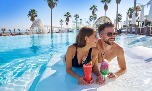 Young couple enjoys vacation in pool with cocktails