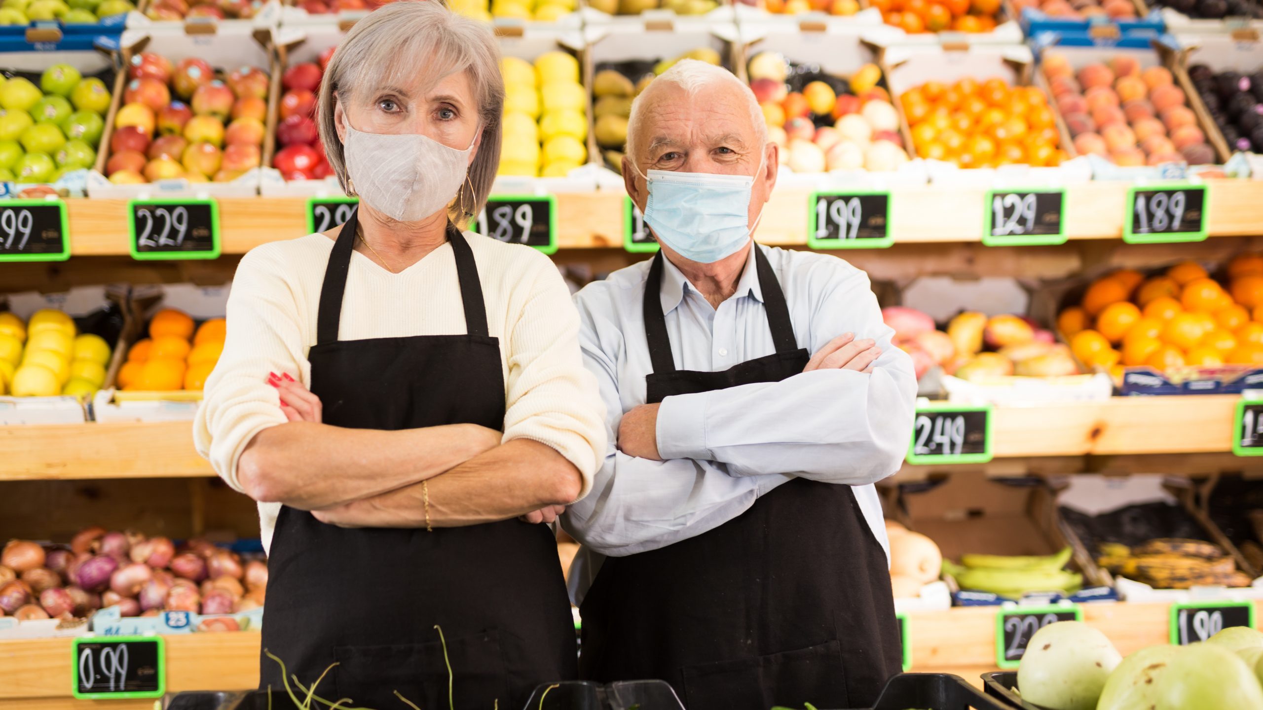 Mature workers in produce section of grocery store