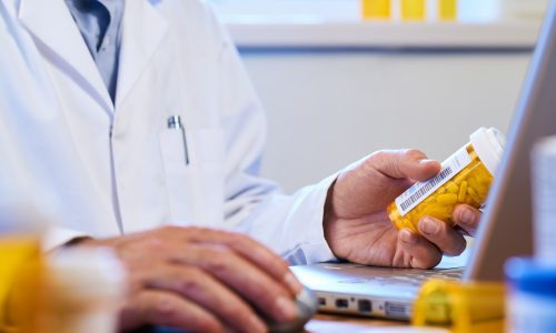 Pharmacist holds bottle of prescription drugs
