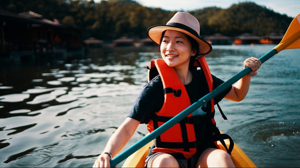 Young woman kayaking in life vest and hat