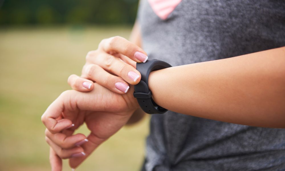 Woman checks Fitbit fitness watch