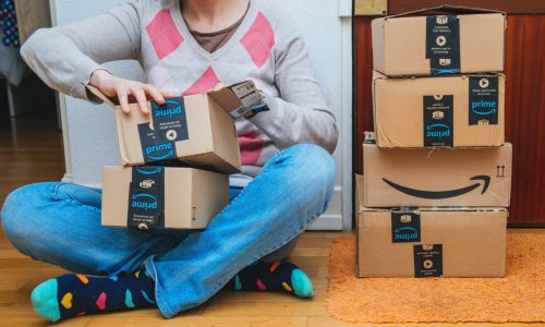 Woman opens multiple Amazon Prime cardboard boxes.