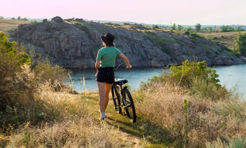 Woman looks at ocean with cruiser bike
