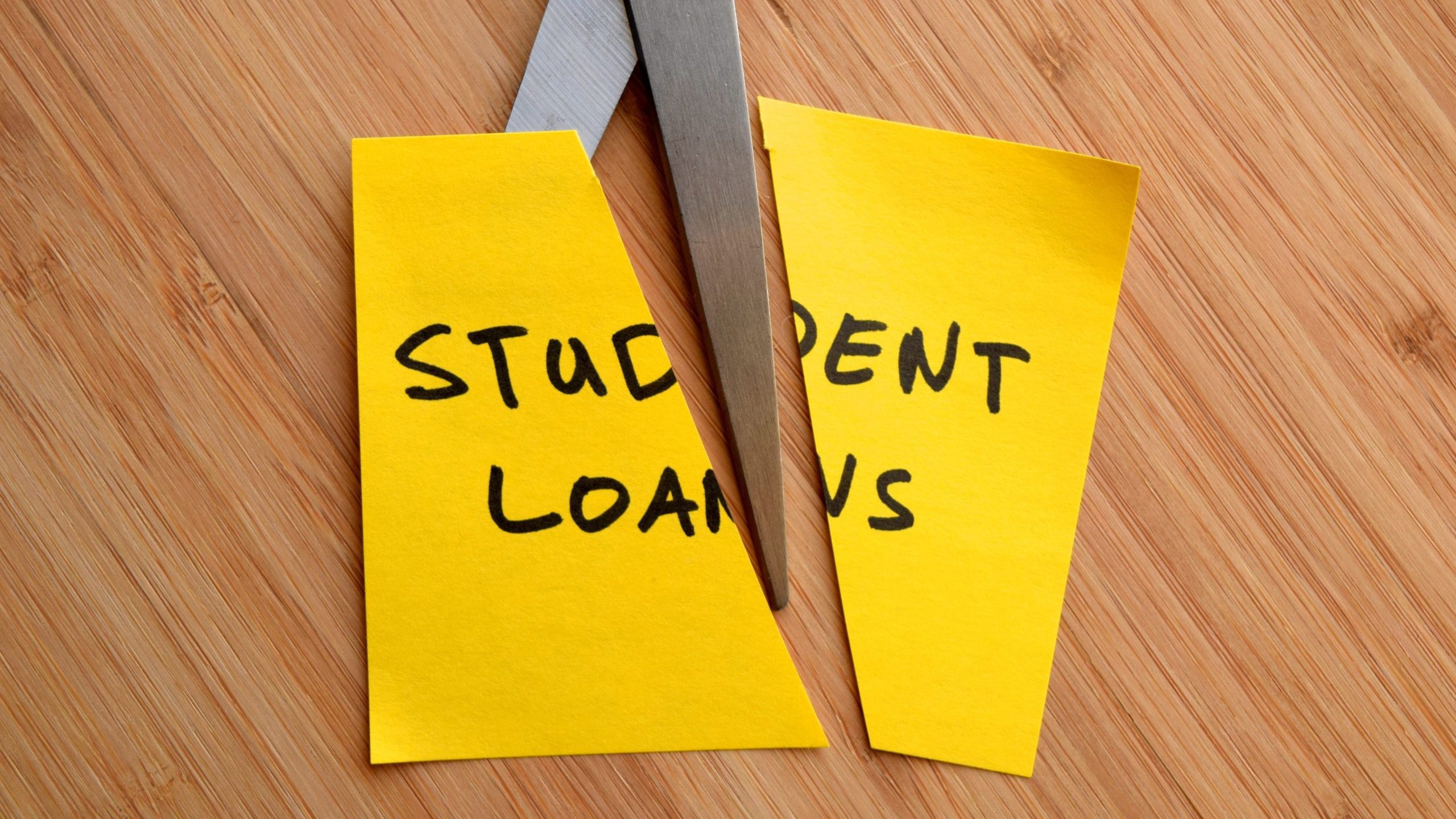 'Student loans' on post-it note cut by scissors
