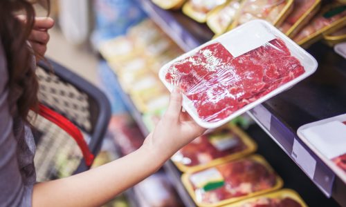 Woman holding beef package at grocery store