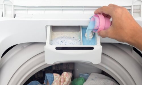 a hand pours fabric softener into washing machine