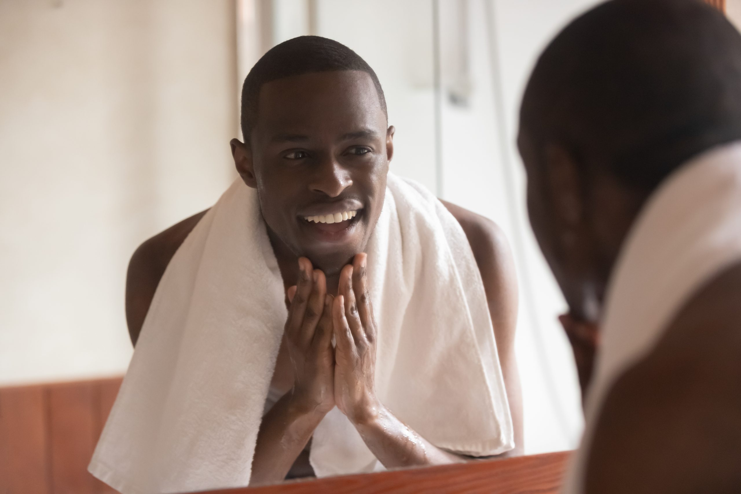 man looking in mirror cleaning face after shaving