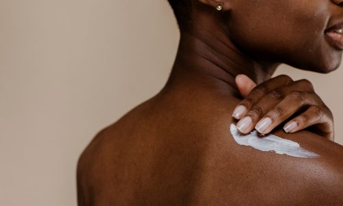 Woman applies moisturizing cream to shoulder