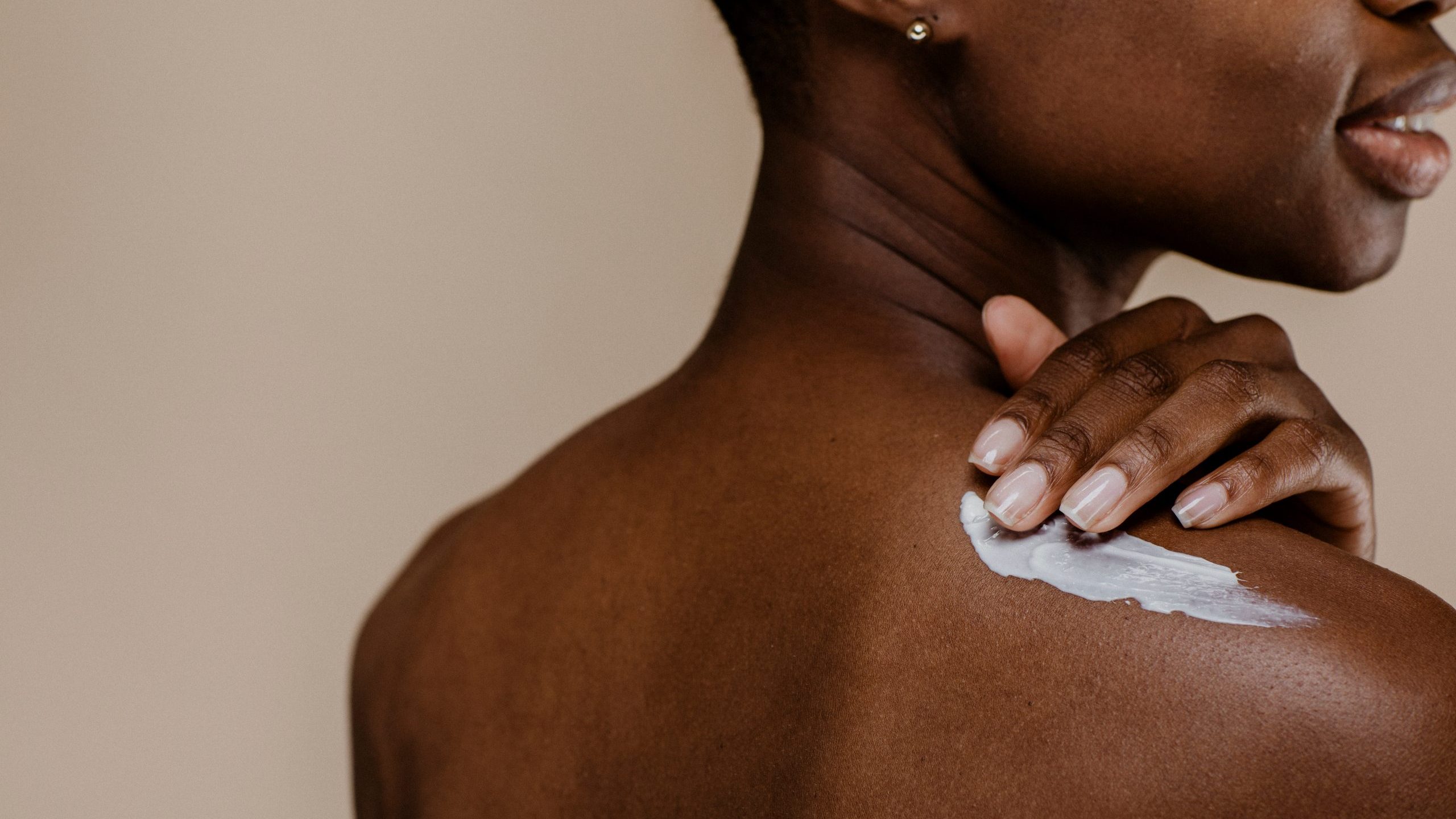 Woman applies moisturizing cream to shoulder