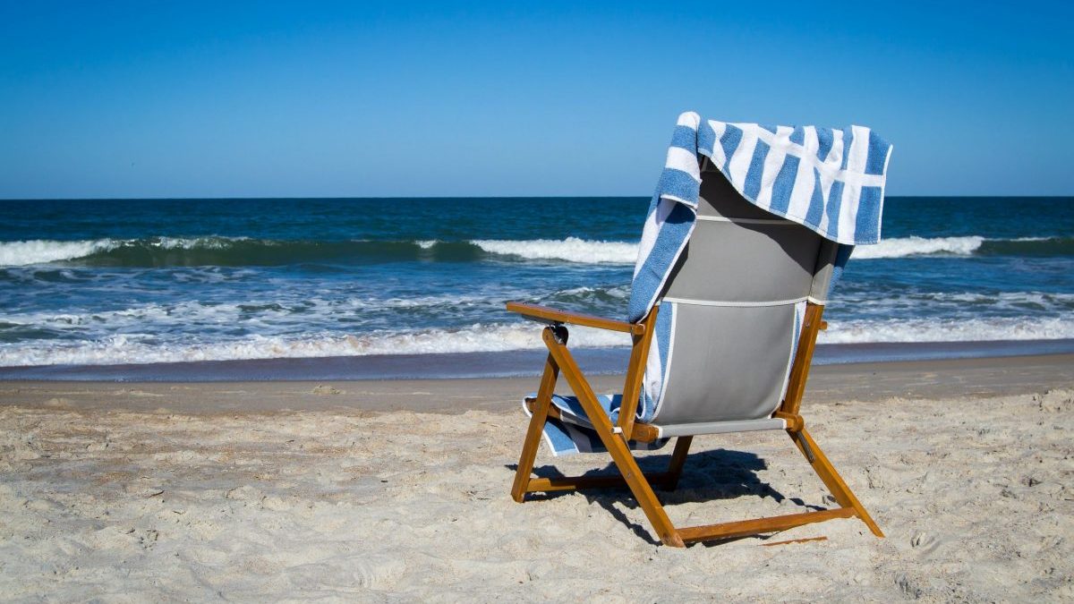 Resort chair with beach view and a towel draped on it.