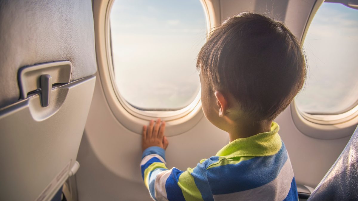 Small child looks out airplane window