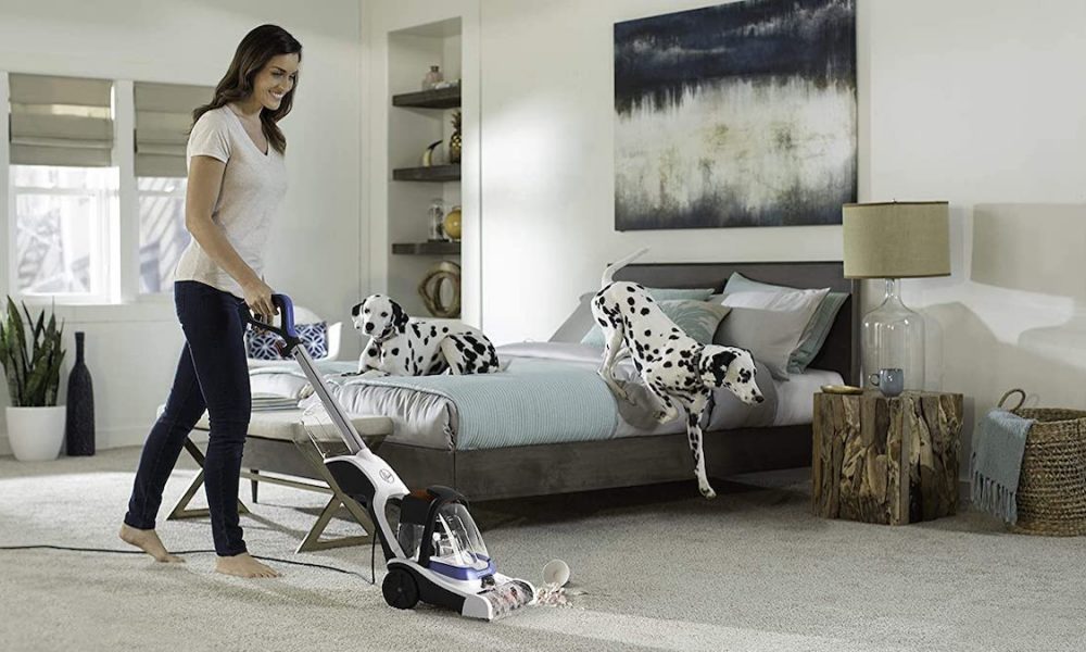 A woman uses the Hoover PowerDash carpet cleaner in her bedroom.