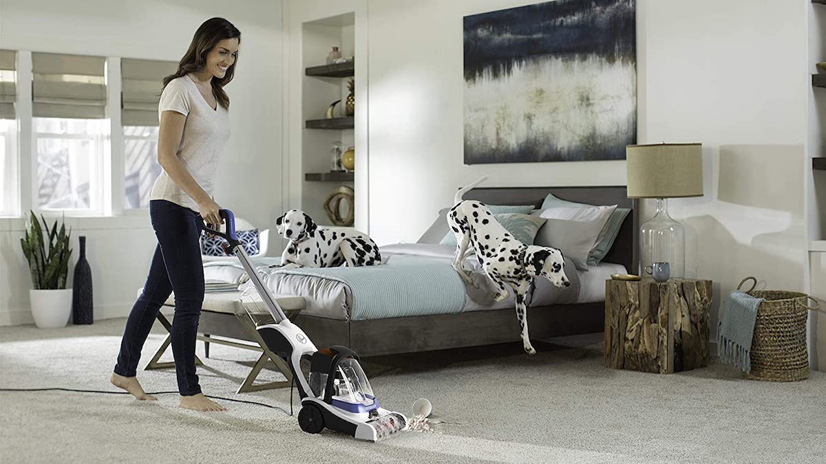 A woman uses the Hoover PowerDash carpet cleaner in her bedroom.
