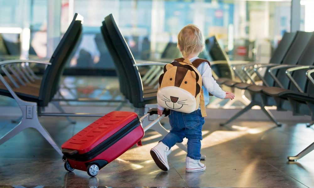 A young child wheels their suitcase through an airport terminal.