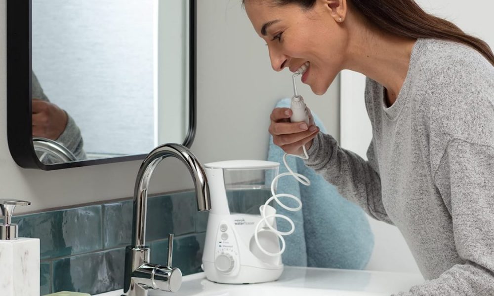 Woman using Waterpik Aquarius Flosser in front of her bathroom mirror.
