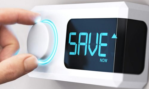 A hand turns a thermostat down with the word "Save" displayed on the readout.