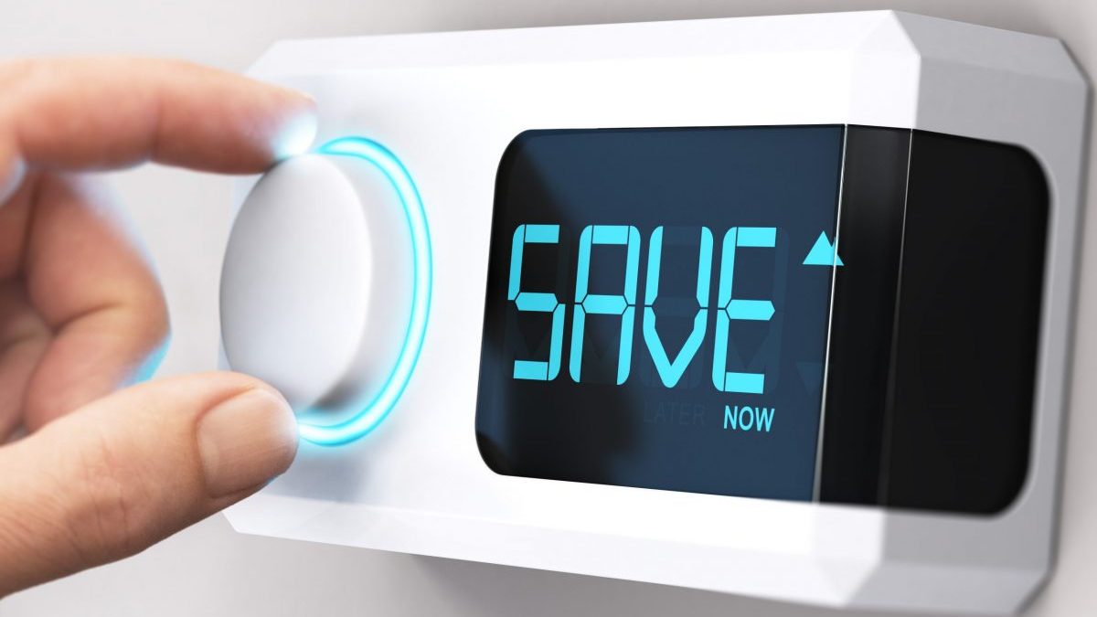 A hand turns a thermostat down with the word "Save" displayed on the readout.