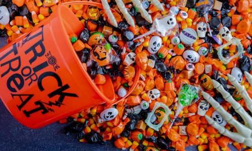 Orange trick or treat pail spilling Halloween candy
