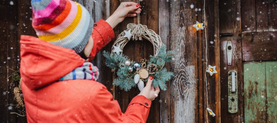 Person hangs twig wreath on door for Christmas holidays