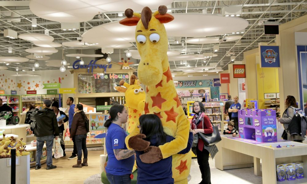 Girl hugs Toys R Us mascot Geoffrey