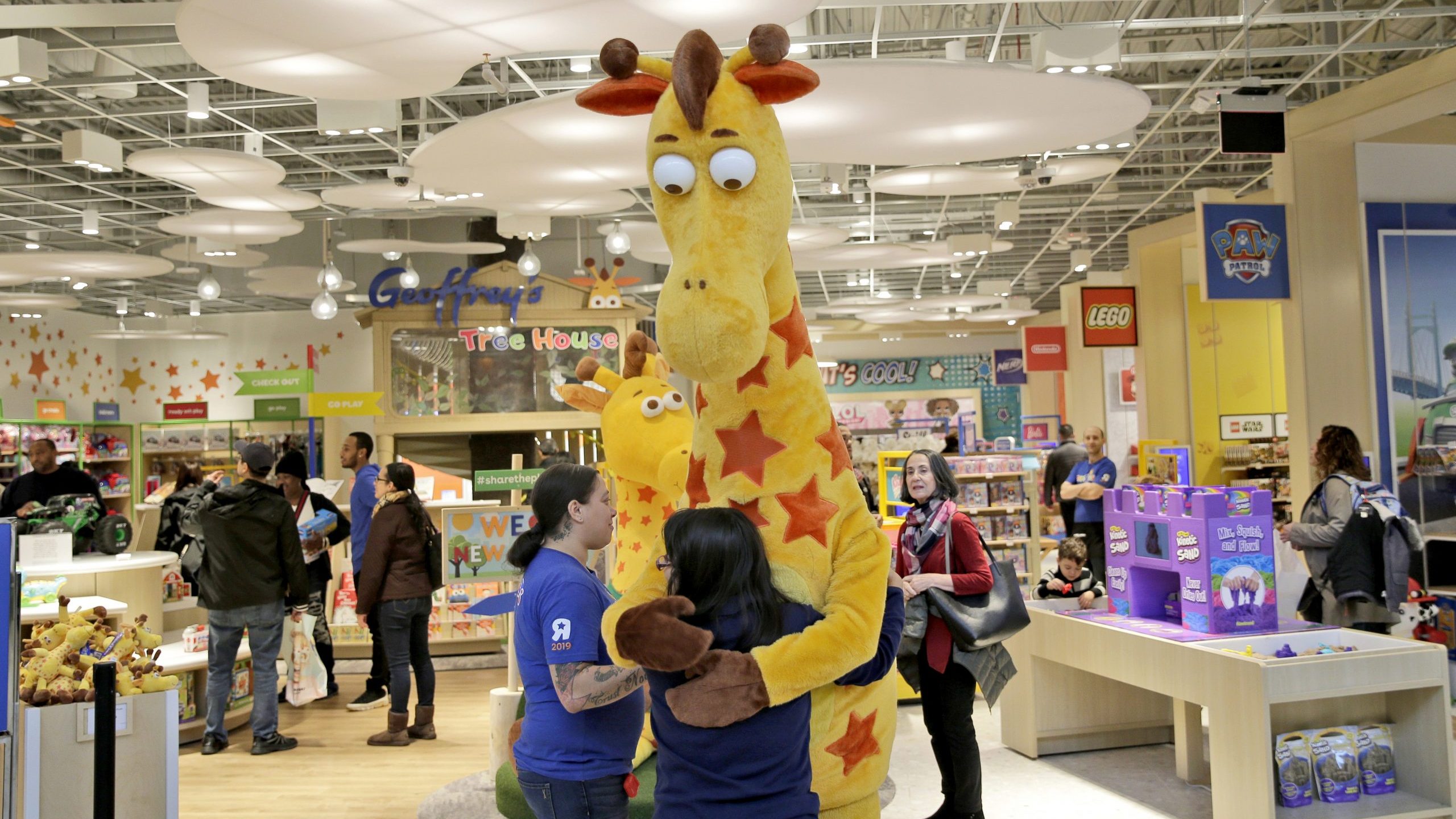 Girl hugs Toys R Us mascot Geoffrey