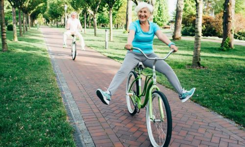 An older woman shows off while riding a bicycle.