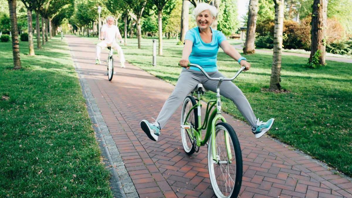 An older woman shows off while riding a bicycle.