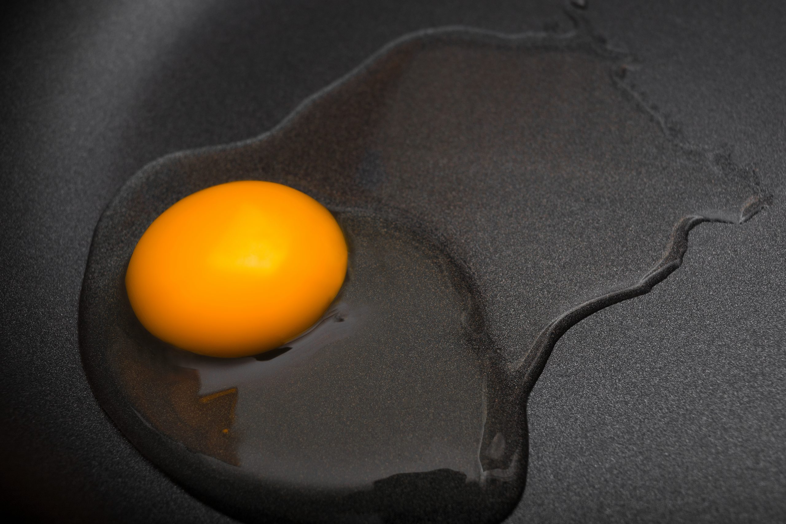 Raw egg on Teflon non-stick frying pan close-up