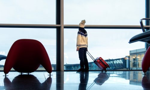 Winter traveler in airport wears sweater, hat