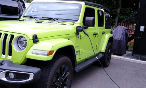 A green Jeep Wrangler 4xe is plugged in.