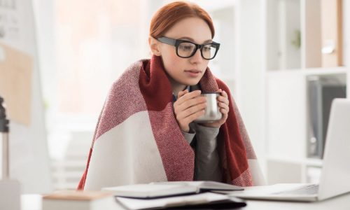 A cold woman works in her office.
