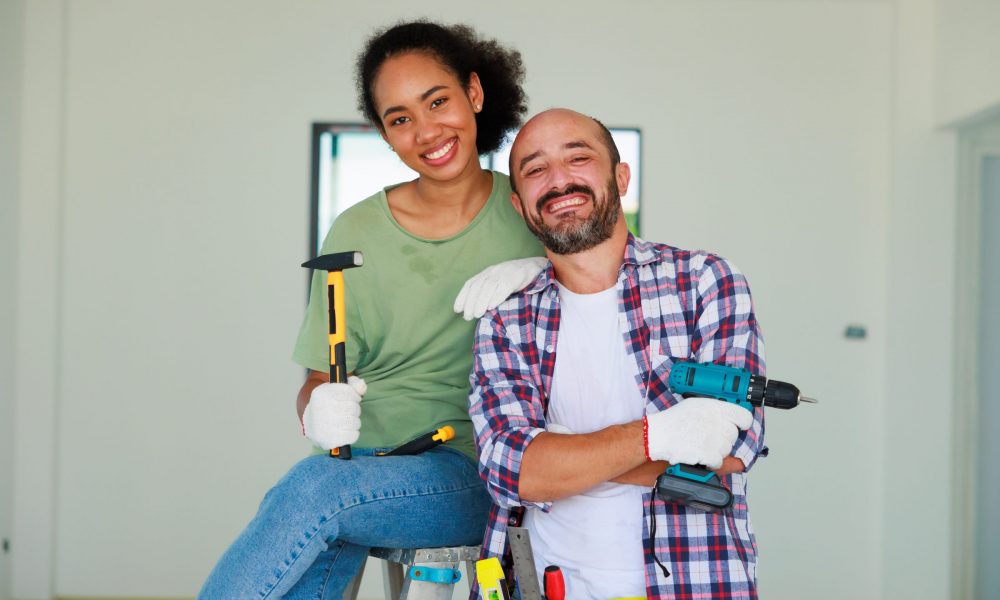 Happy couple holding tools for DIY home projects