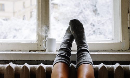 Feet on windowsill in house during winter