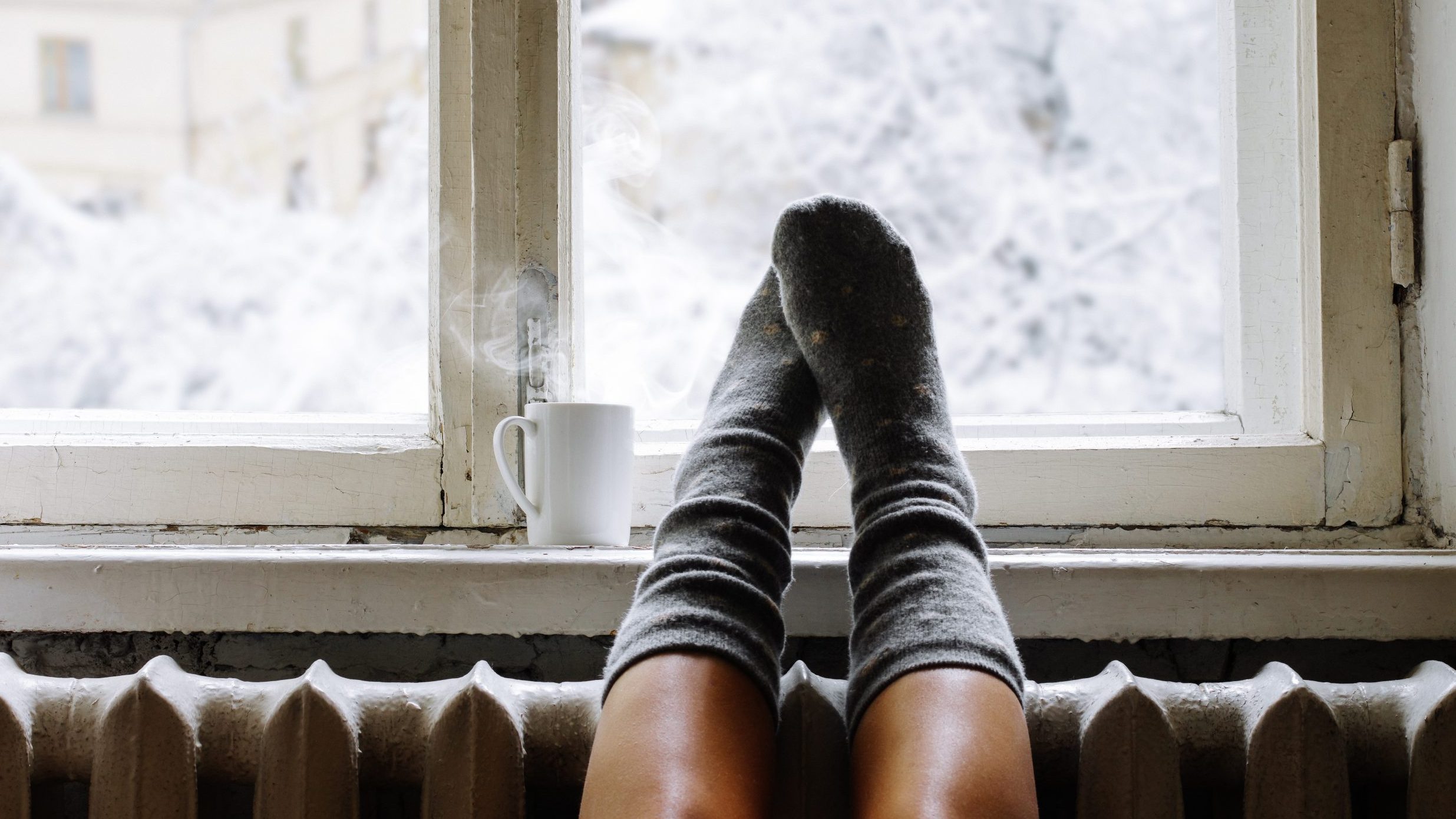 Feet on windowsill in house during winter