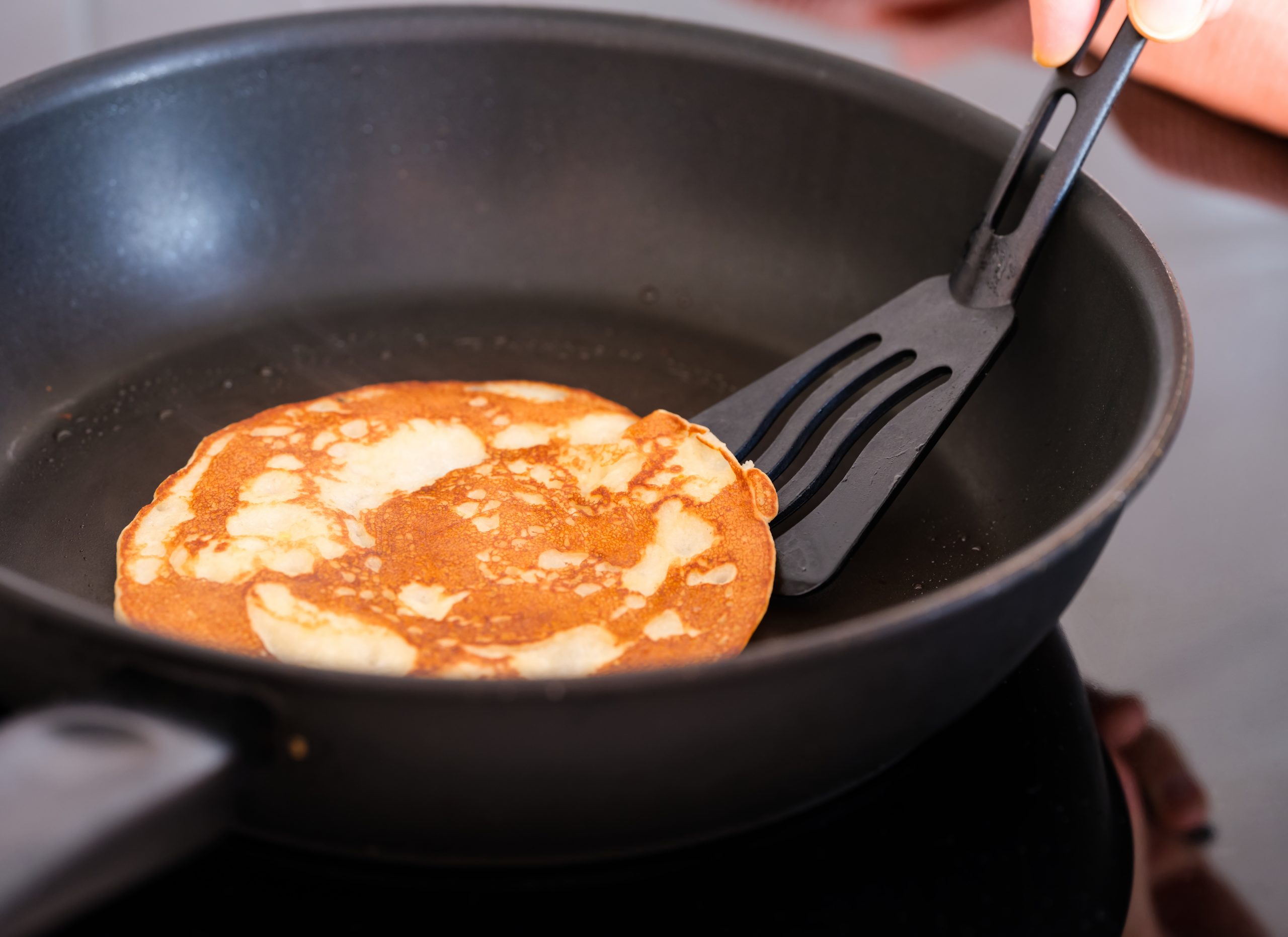 pancake being flipped by a black spatula 