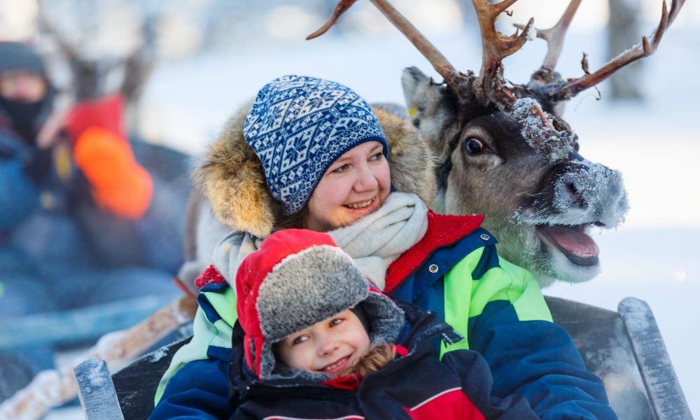 Happy people in snowy scene with reindeer in background