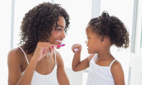 mom and little girl brush their teeth