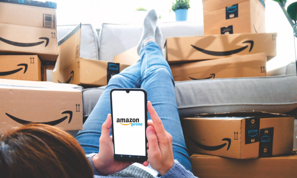 Shopper looks at Amazon app on phone, surrounded by packages