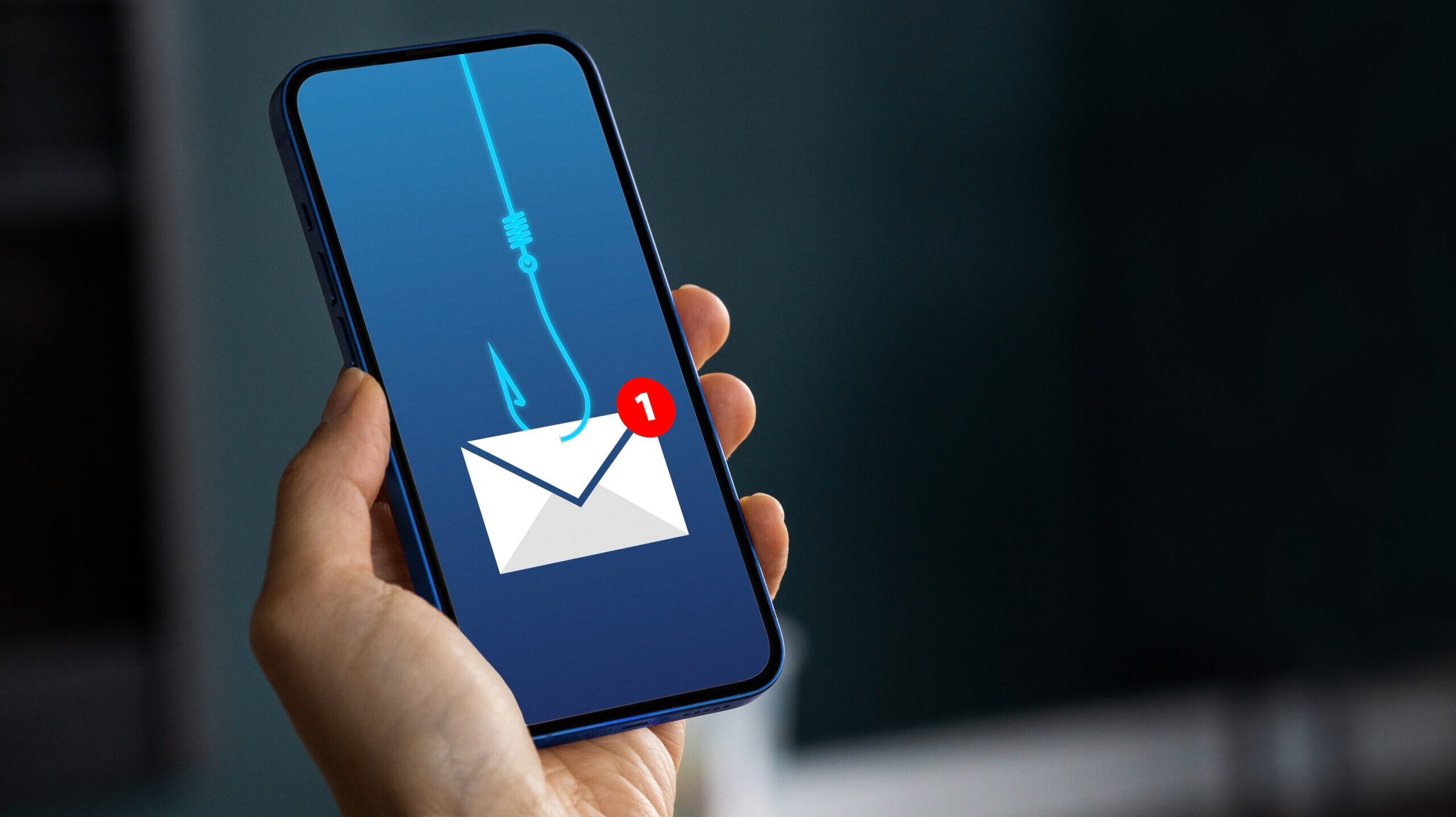 Hand holds phone showing email phishing illustration