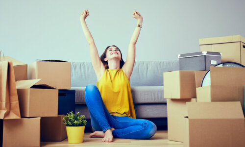 Happy woman celebrates moving amid boxes