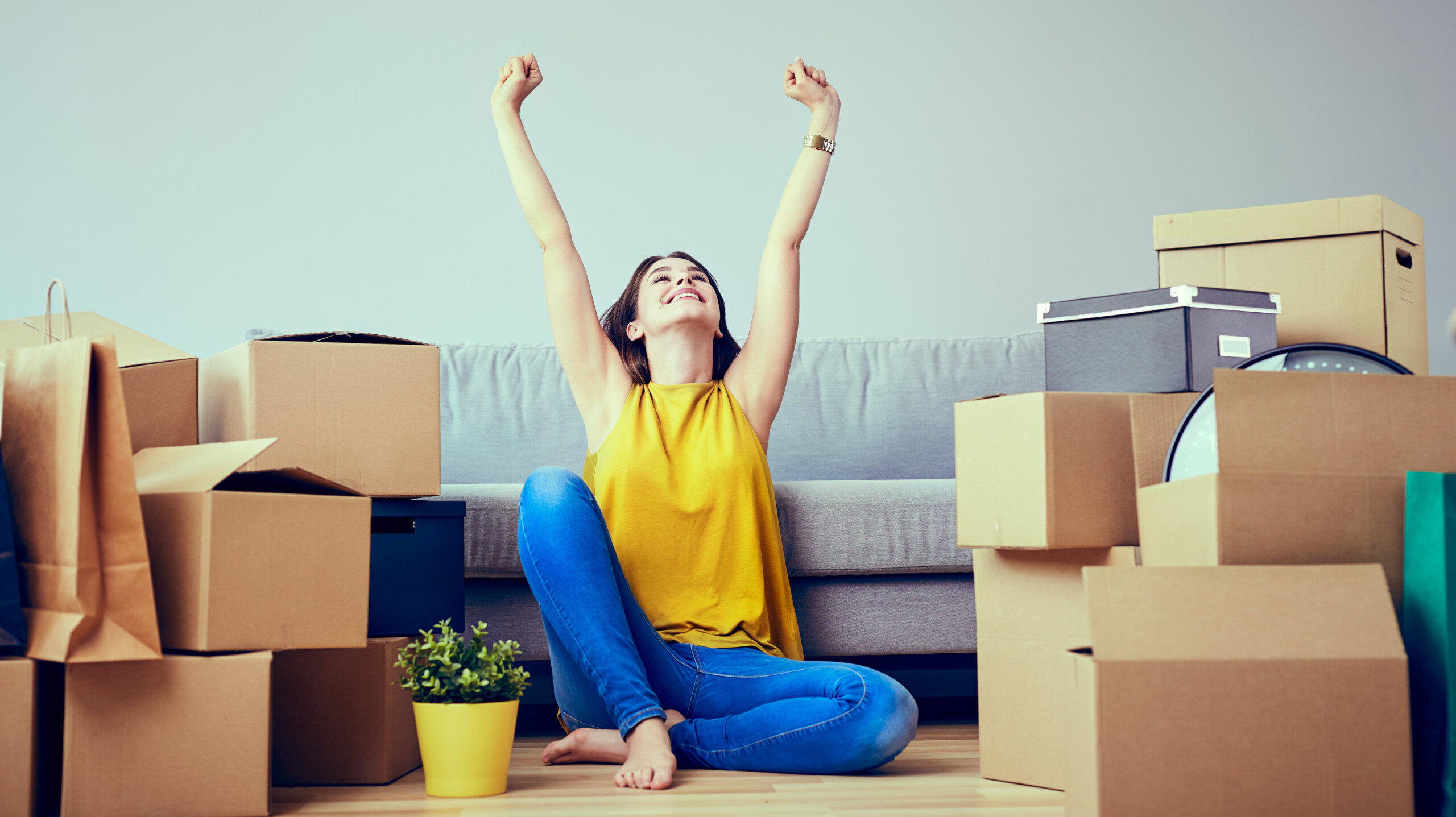Happy woman celebrates moving amid boxes