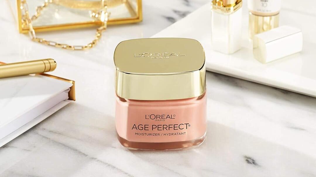 A jar of L'oreal Paris Age Perfect Rosy Tone Anti-Aging Moisturizer sits on a marble vanity.
