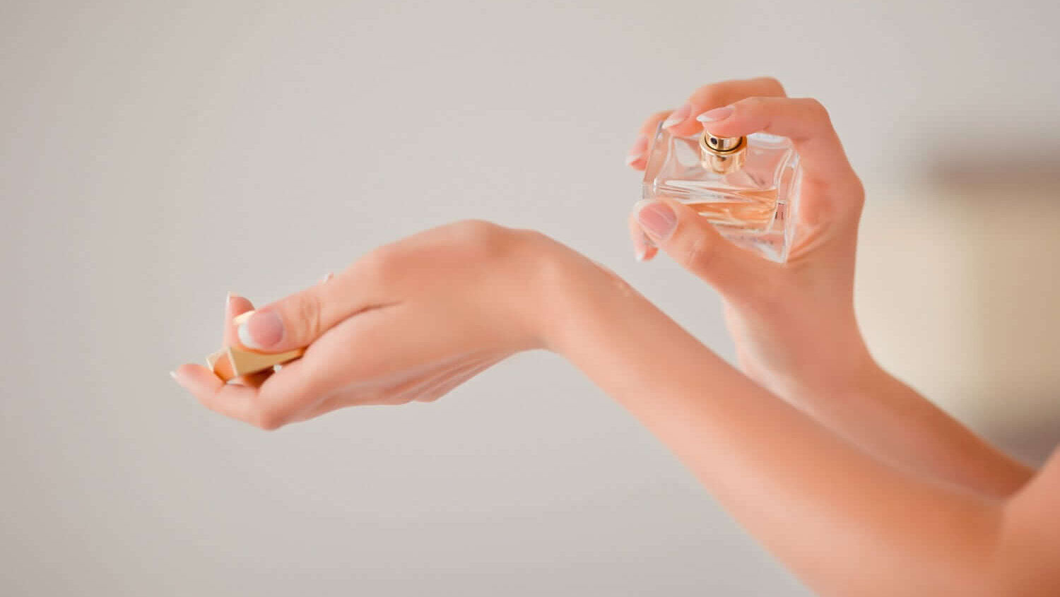 Woman putting perfume on wrist
